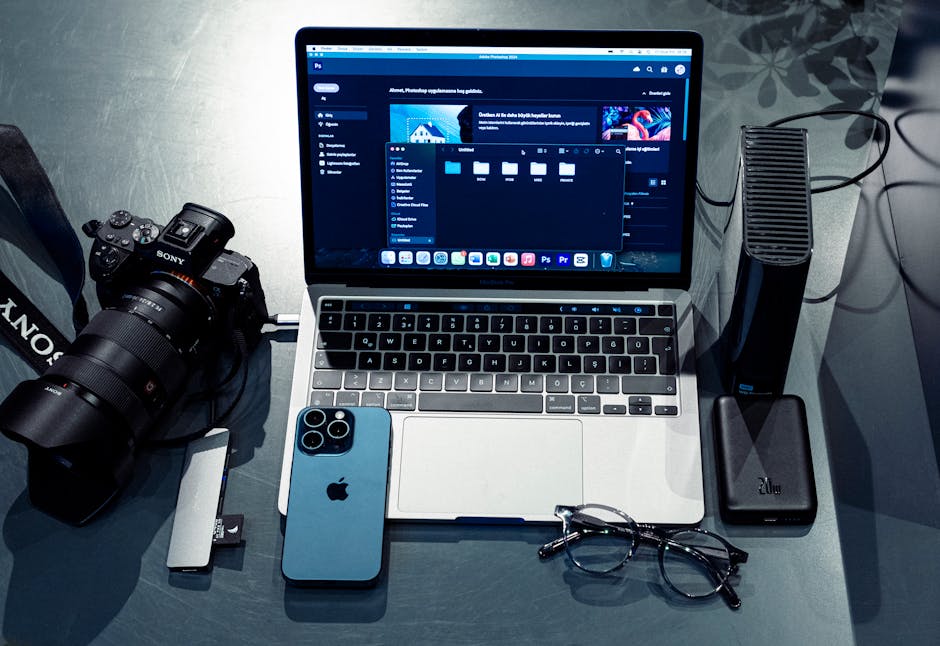 Modern workspace setup featuring a laptop, smartphone, camera, and accessories for digital creativity.
